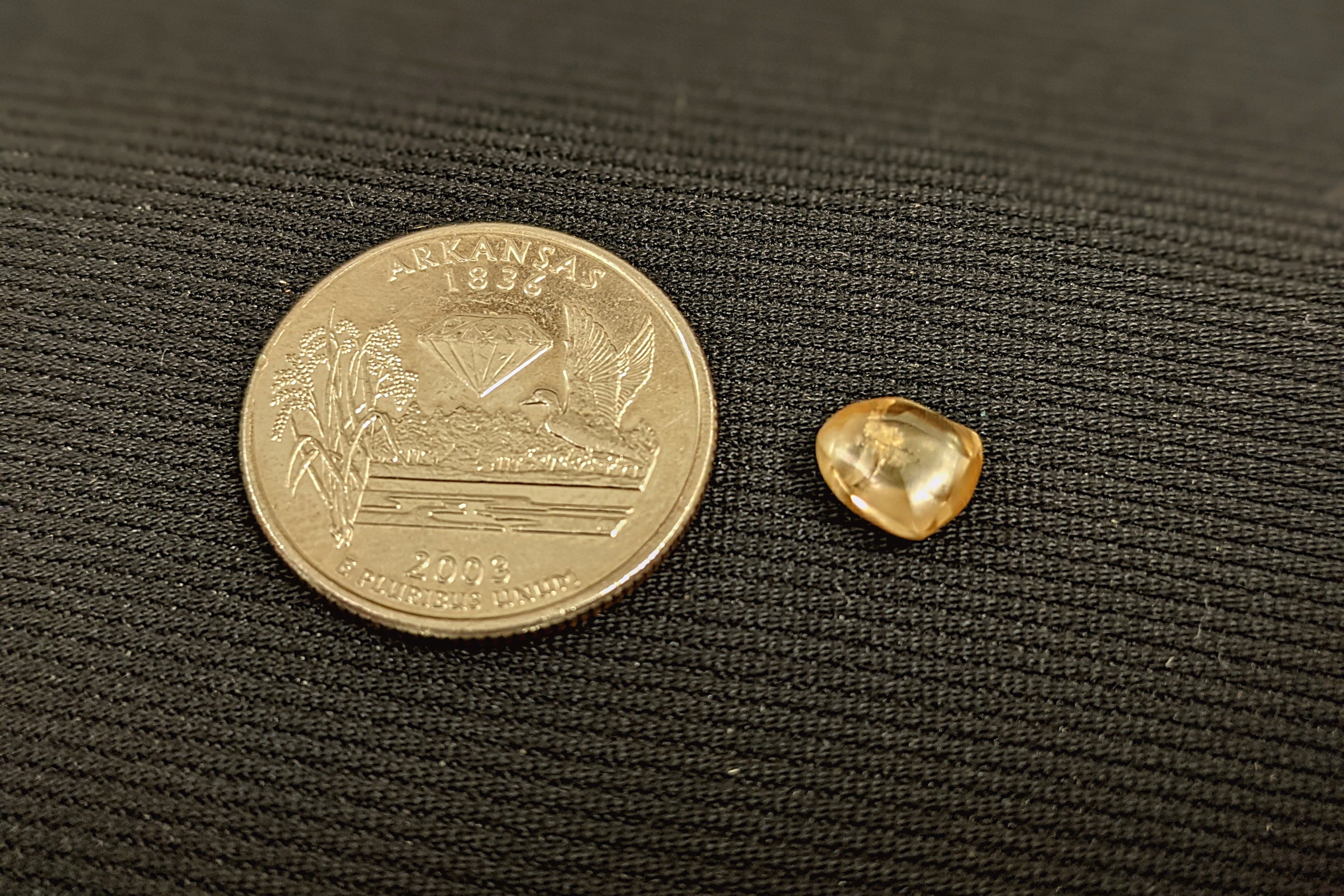2.20 carat yellow diamond sitting next to a quarter for scale